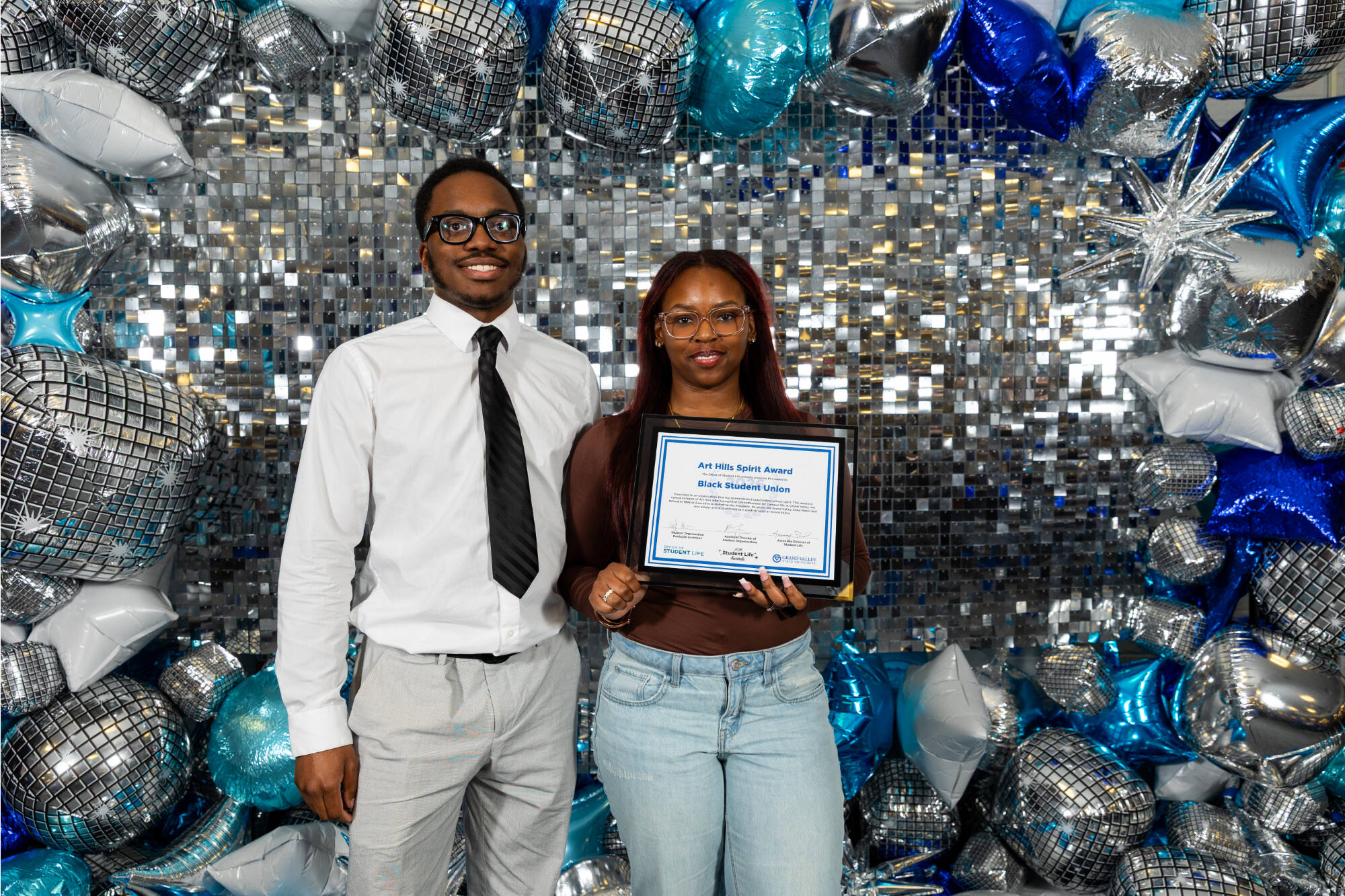 Two individuals holding an award certificate